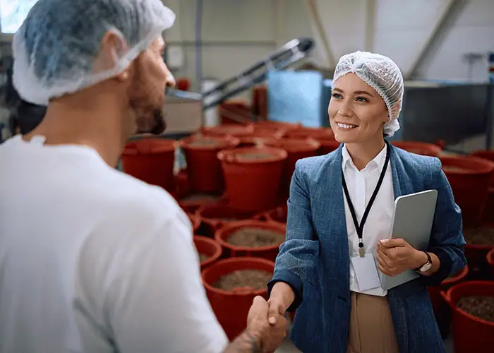 Supplement ingredient supplier and contract manufacturer partnership handshake inside nutraceutical raw material production facility