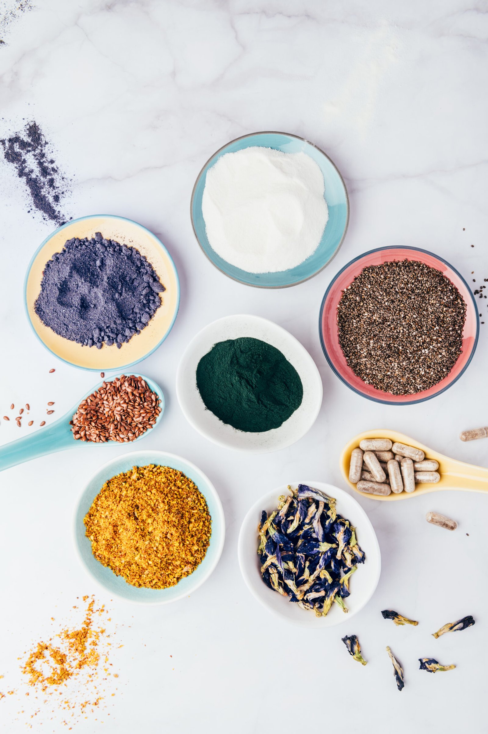 Variety of healthy food supplements such as blue matcha, butterfly pea flowers, collagen powder, spirulina powder, vitamins for vegans and vegetarians, flax and chia seeds,