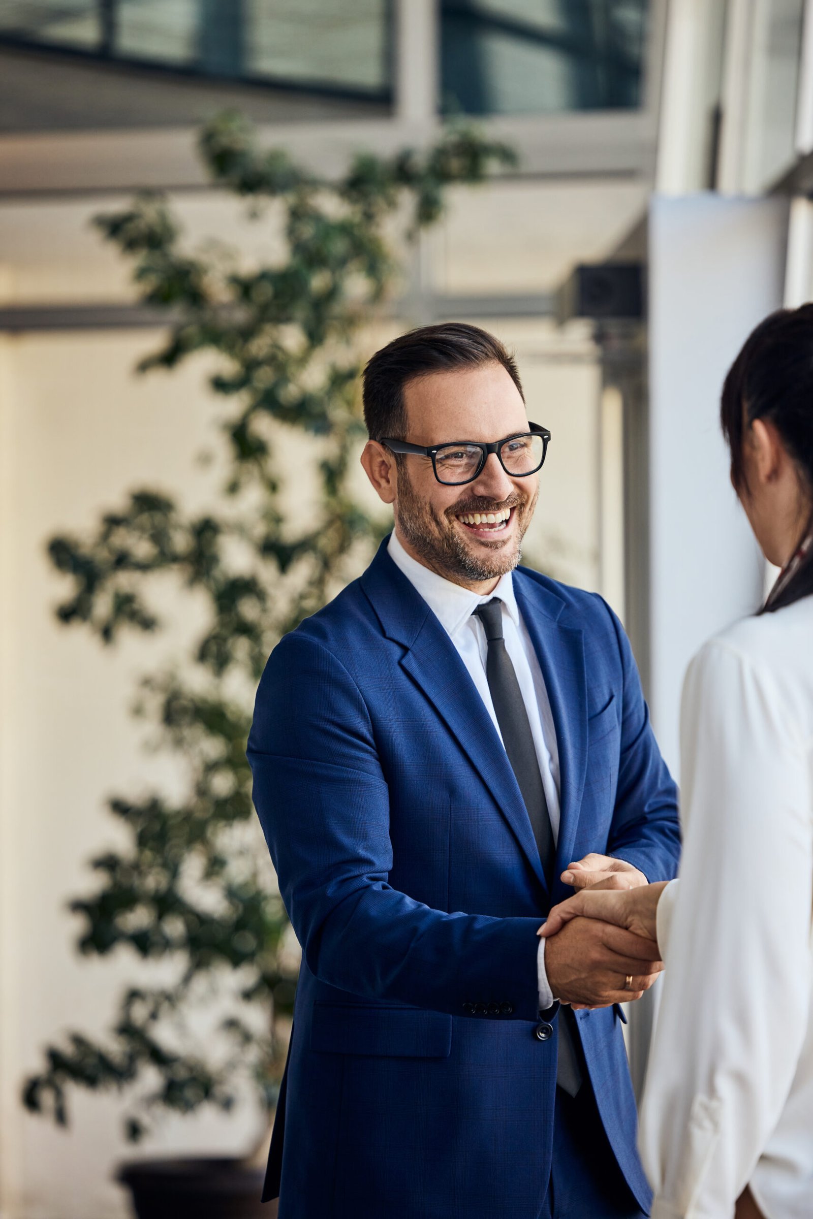Professional colleagues exchanging a handshake in a corporate office setting.